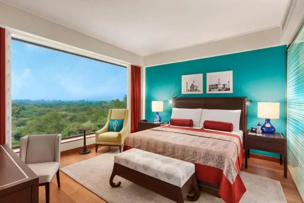 Helles Zimmer mit Doppelbett und großer Fensterwand mit Blick ins Grüne
