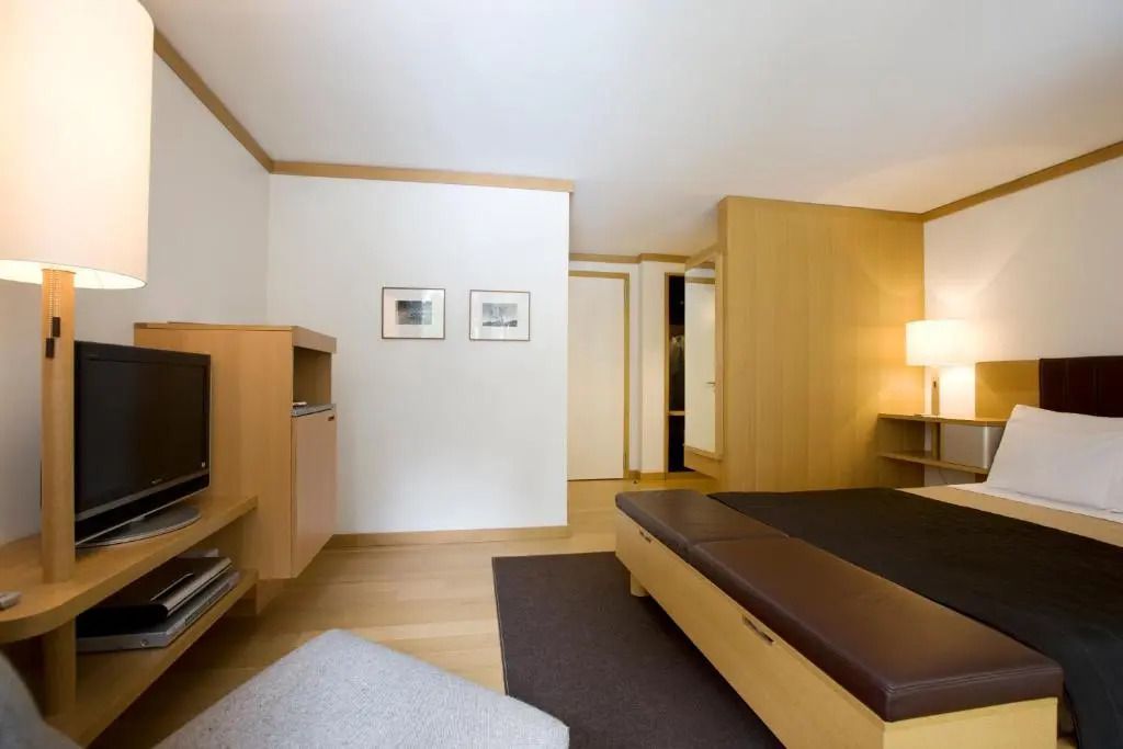 Helles Hotelzimmer mit Sessel, Fernseher und minimalistischer Einrichtung