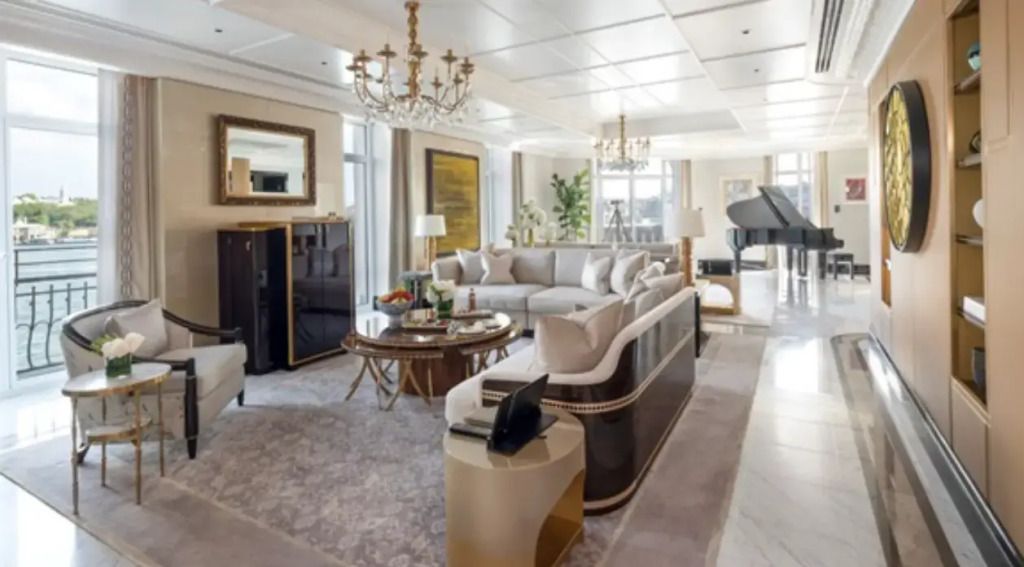 Luxuriöses Wohnzimmer mit edlen Sofas, großem Fenster und Flügel