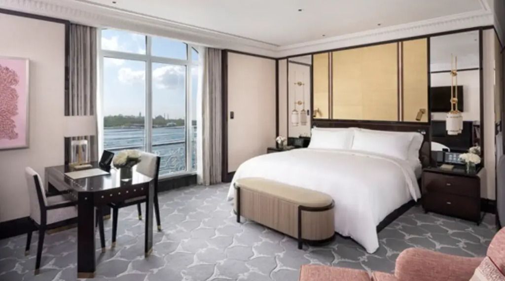 Luxuriöses Hotelzimmer mit Doppelbett und Blick auf den Bosporus durch große Fenster.