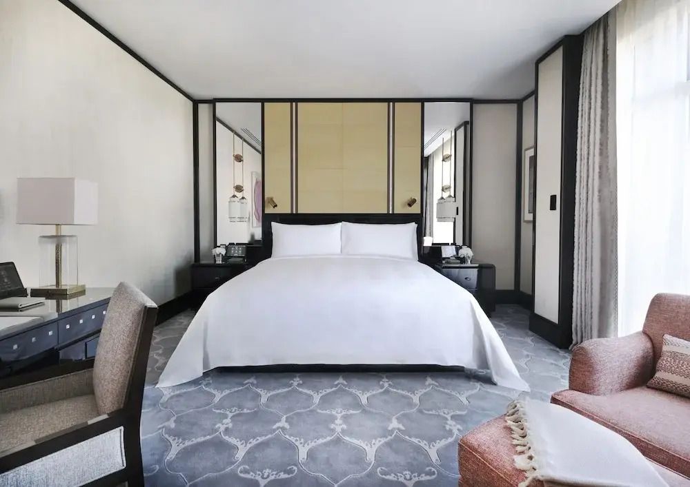 Hotelzimmer mit großem Doppelbett und elegantem Design in neutralen Tönen.