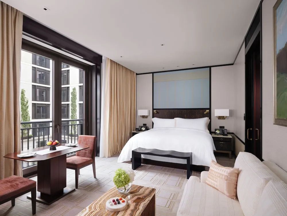 Geräumiges Deluxe Doppelzimmer mit großem Bett und modernen Möbeln. Fensterfront mit Ausblick.