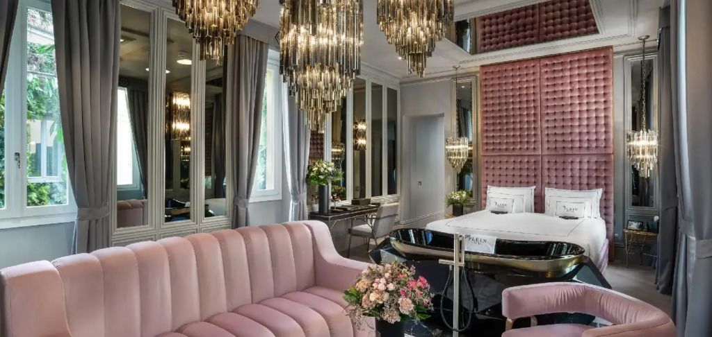Helle Suite mit rosa Sofa und prunkvollen Leuchten