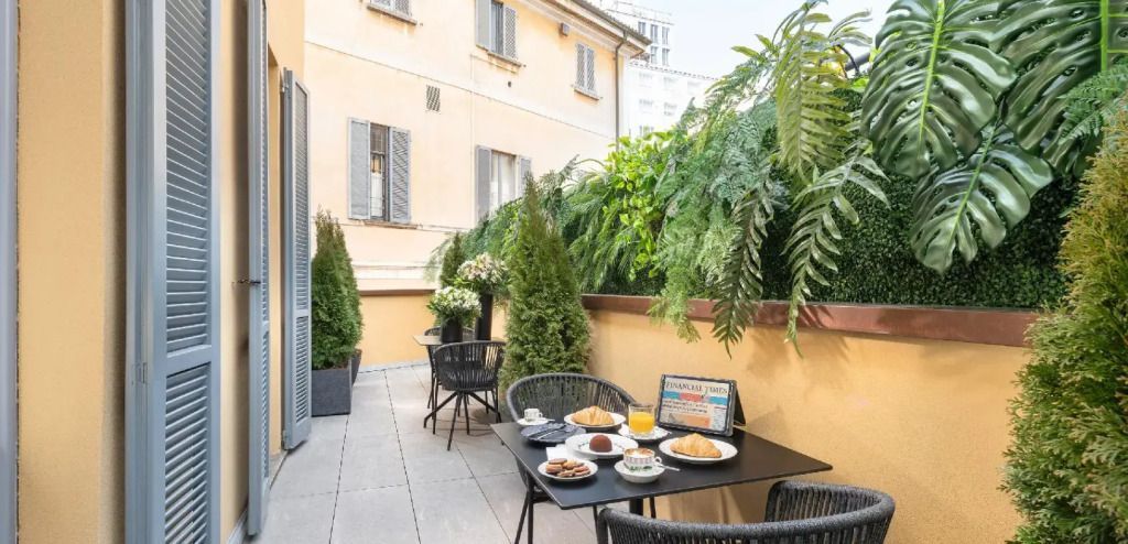 Private Terrasse mit grünen Pflanzen und gedecktem Frühstückstisch