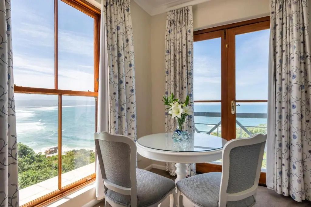 Sitzbereich mit Meerblick durch große Fenster in der Premier Suite