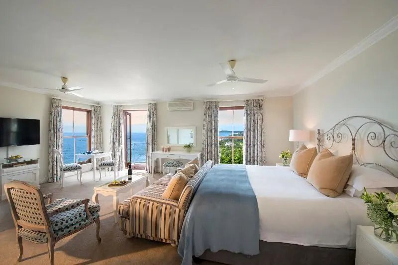 Helles Schlafzimmer einer Suite mit großem Bett und Meerblick durch Fenster