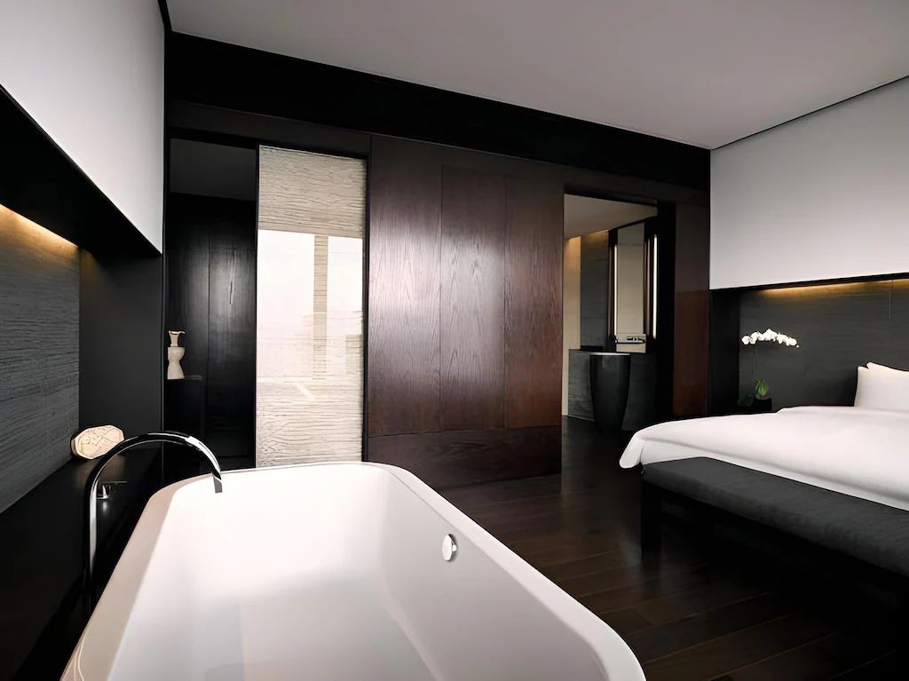 Schlafzimmer der Jing'An Suite mit luxuriöser Badewanne und modernem Design.