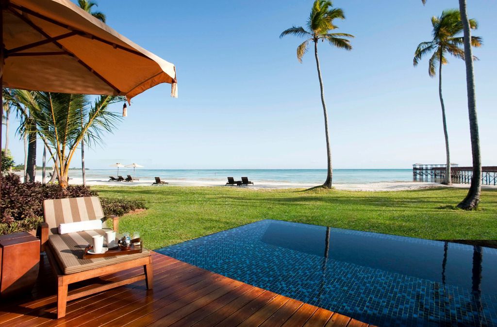 Privater Pool der Frangipani Villa mit Blick auf den Ozean und Palmen an einem sonnigen Strand