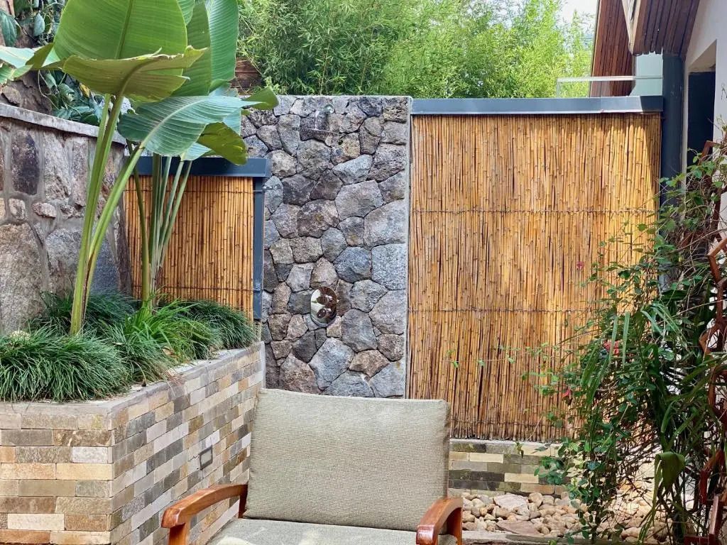 Stein- und Bambuswand mit eleganter Gartenbestuhlung