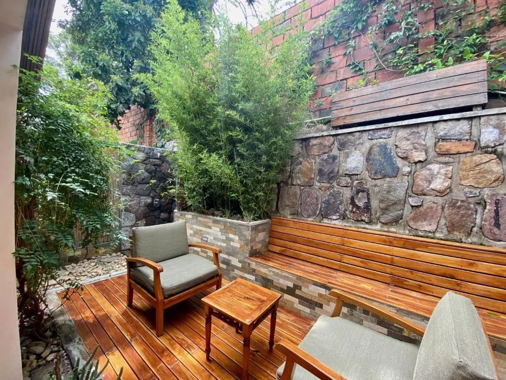 Terrasse mit Holzboden und komfortablen Sesseln umgeben von Pflanzen