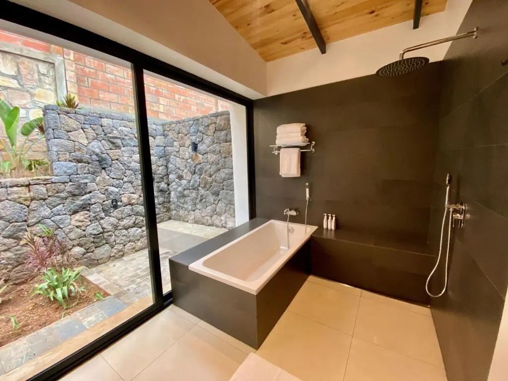 Modernes Badezimmer mit großer Badewanne und Natursteinmauer