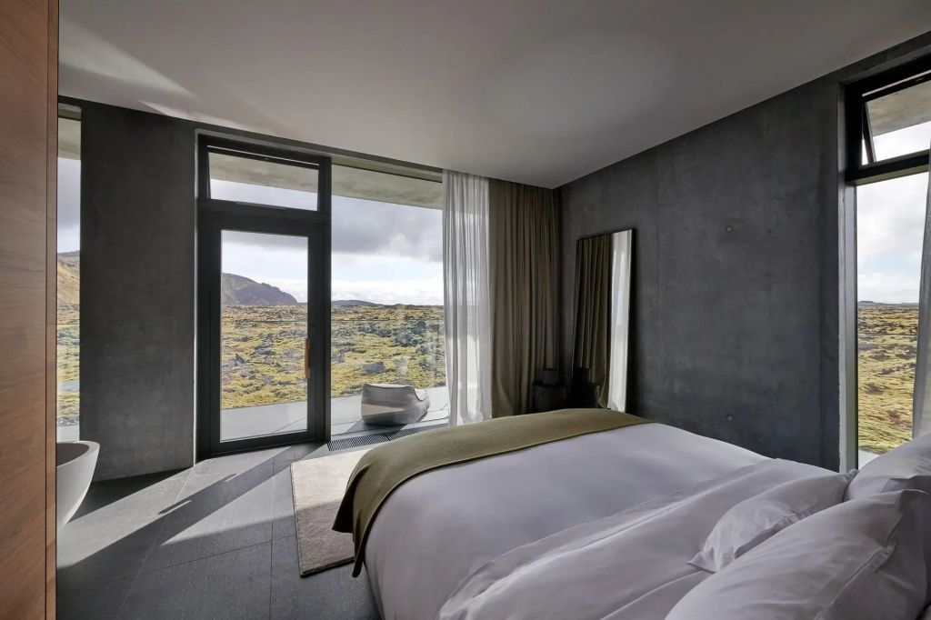 Modernes Hotelzimmer mit großem Fenster, Kingsize Bett und freiem Blick auf vulkanische Berge.