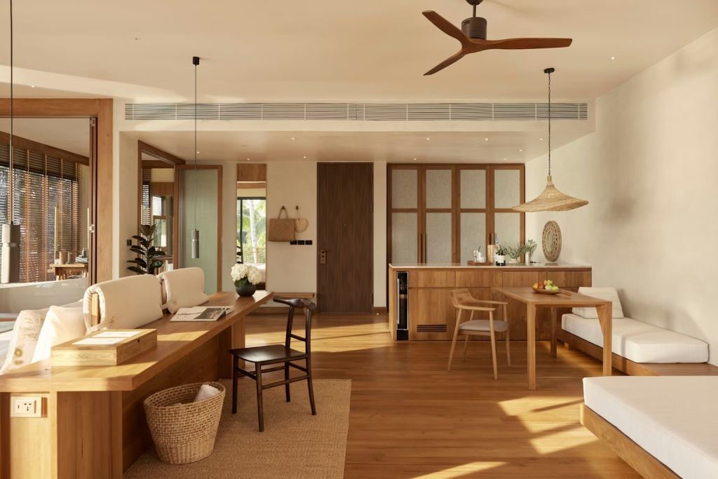 Offenes Wohnzimmer mit Holzmöbeln und Deckenventilator in einer Suite.