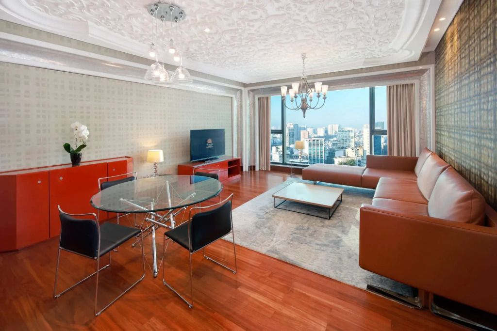 Wohnzimmer mit Ledersofa, Glastisch und großem Fenster mit Stadtansicht