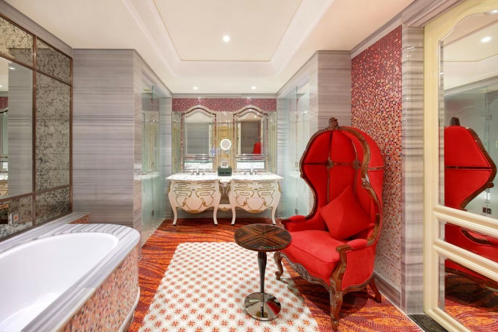 Elegantes Badezimmer mit zwei Waschbecken und einem opulenten roten Sessel