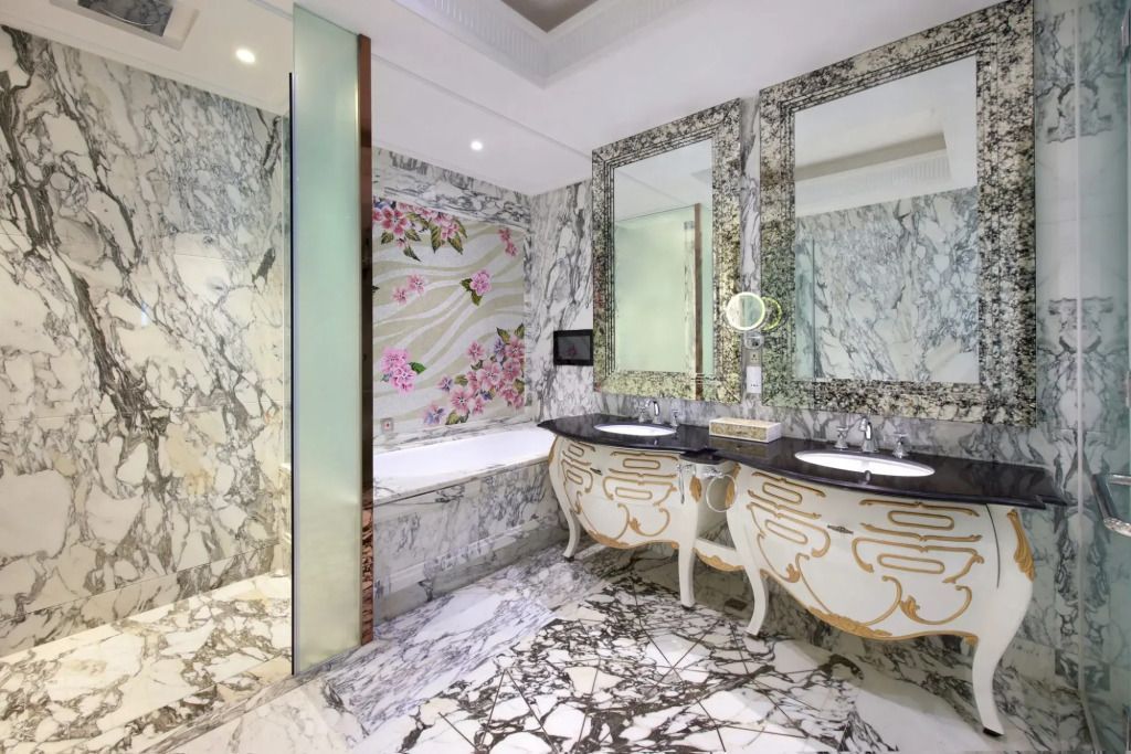 Edles Badezimmer mit Marmorfliesen und kunstvoll verzierter Badewanne.