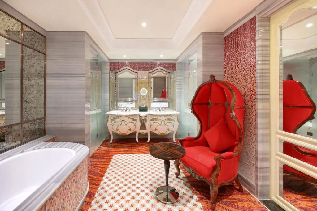 Elegantes Bad mit rotem Sessel und luxuriöser Ausstattung im Hotel