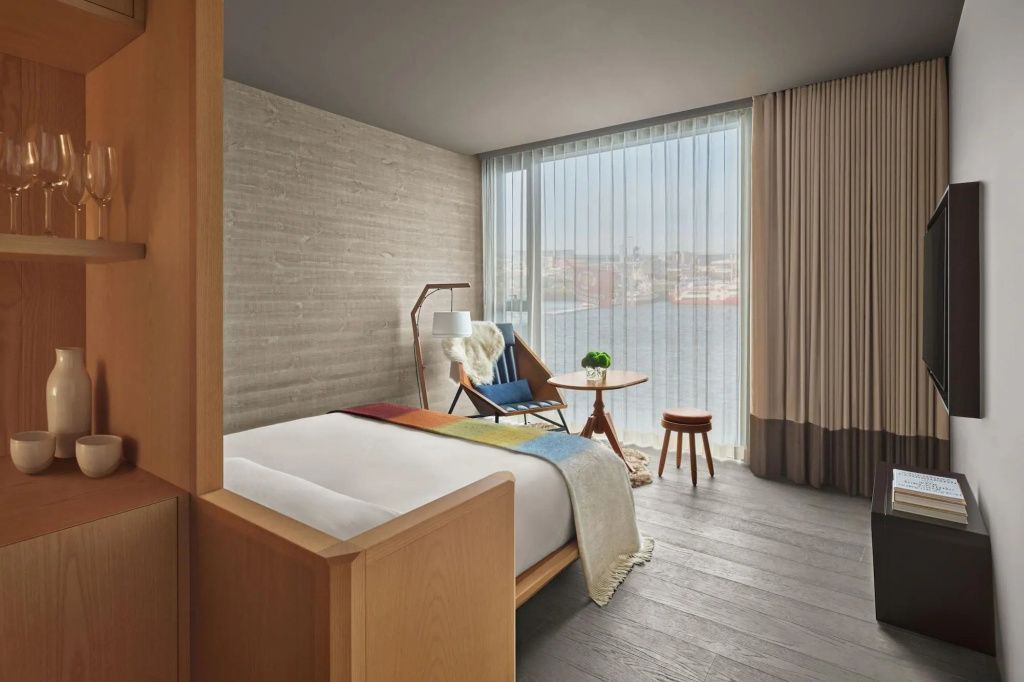 Luxuriöses Hotelzimmer mit Holzmöbeln und Blick durch ein Panoramafenster auf den Hafen
