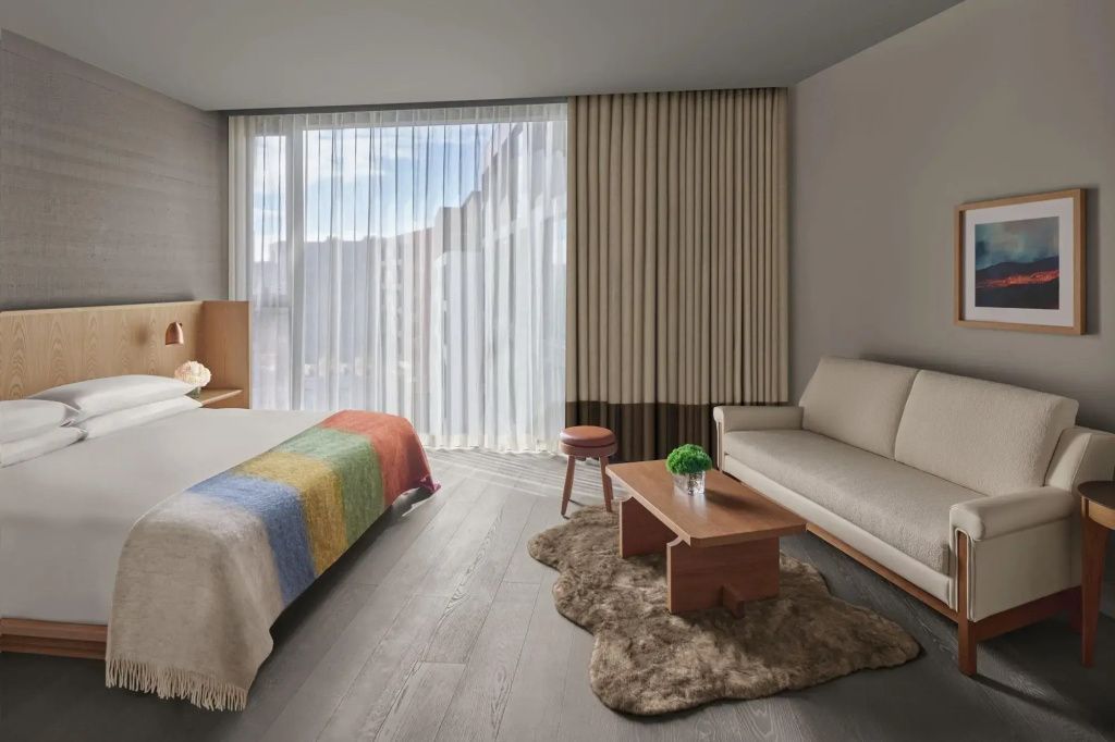 Geräumiges Hotelzimmer mit bequemem Sofa, Couchtisch auf Fellteppich und großem Bett