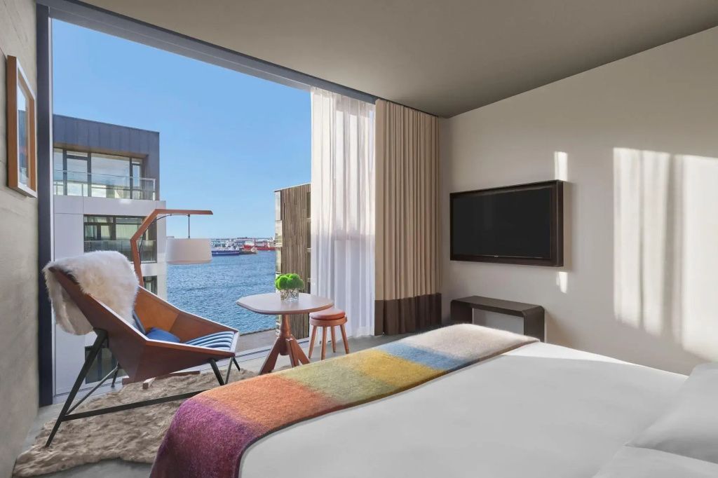 Modernes Hotelzimmer mit Flachbildfernseher, gemütlicher Sitzecke und Blick auf das Meer