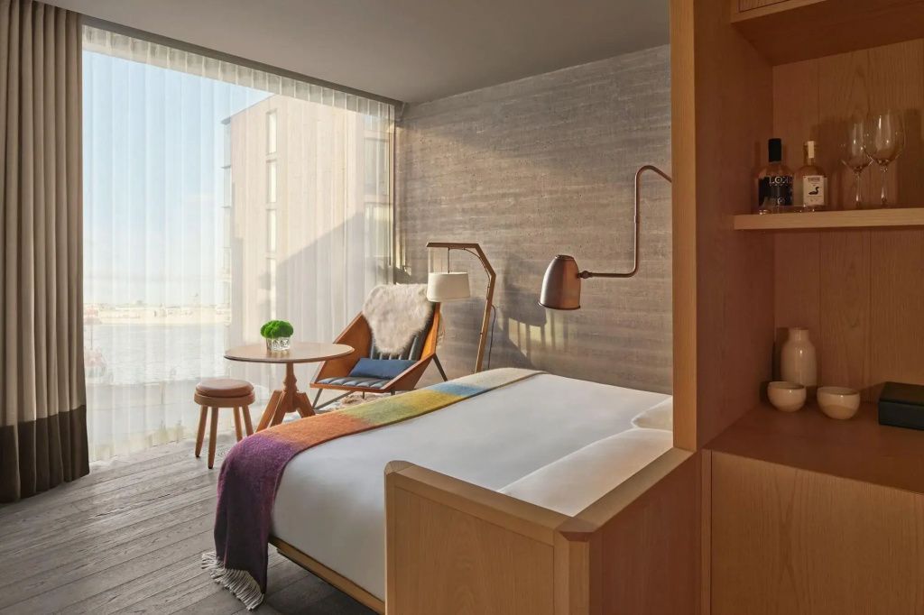 Gemütliches Bett und Designer Sessel am Fenster in einem modernen Hotelzimmer