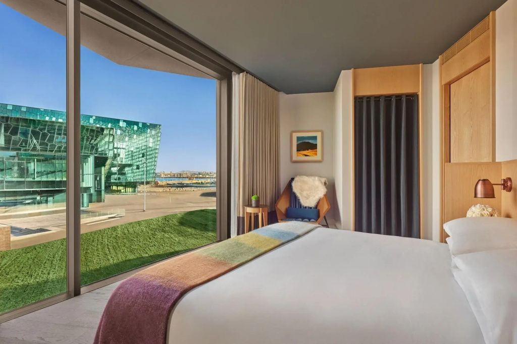 Zimmer mit bodentiefem Fenster und Panoramaaussicht auf das Harpa Konzertgebäude in Reykjavik.