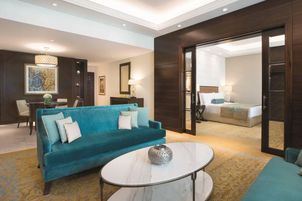 Wohnbereich der Suite mit Blick ins Schlafzimmer und eleganter Beleuchtung.