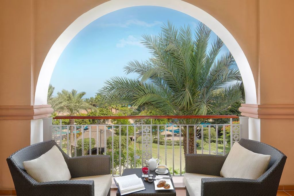 Balkon mit Blick auf Palmen und Garten mit Sitzgelegenheit