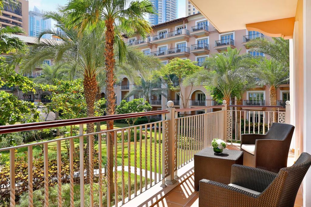 Balkon mit Sitzgelegenheiten und Blick auf tropischen Garten und Palme