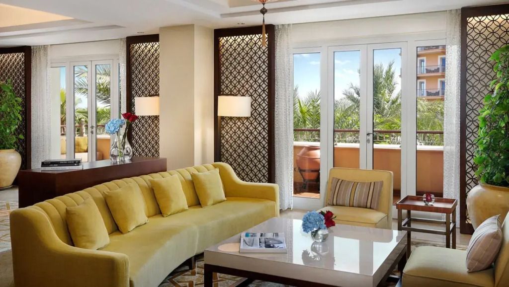 Wohnzimmer mit gelbem Sofa, Tisch und Balkon mit Pflanzen