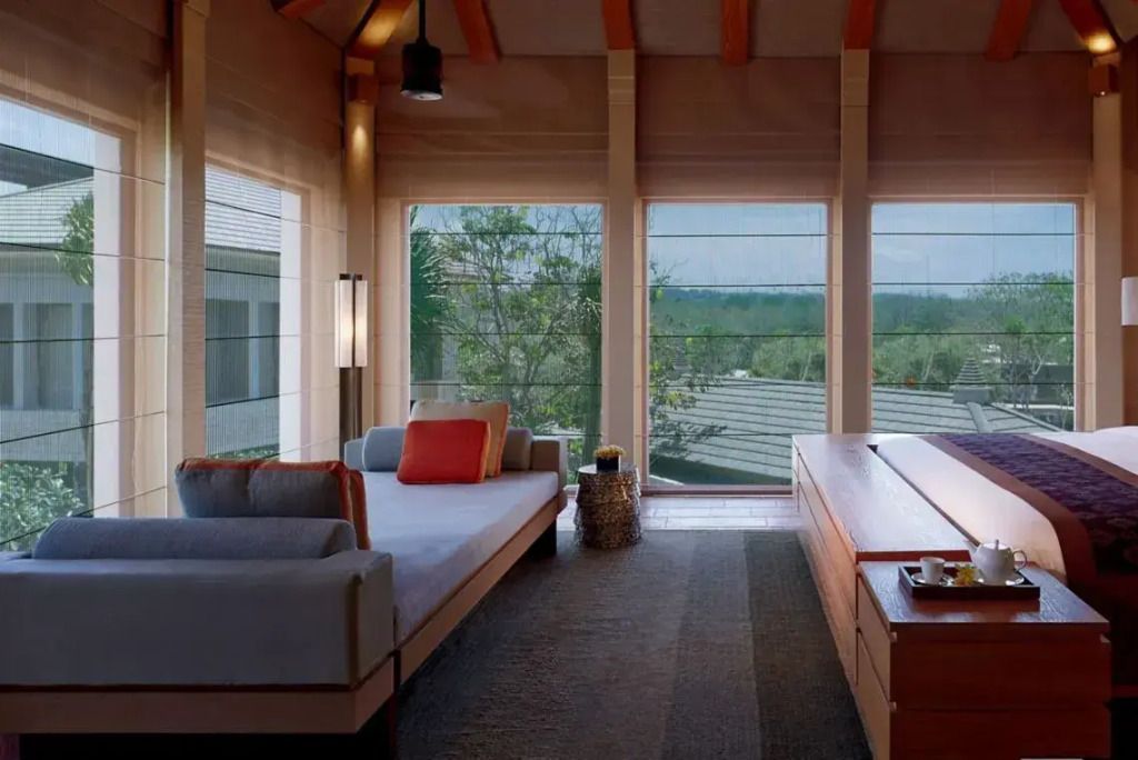 Komfortabler Wohnbereich mit Sofa und großen Fenstern mit Blick auf die grüne Umgebung.