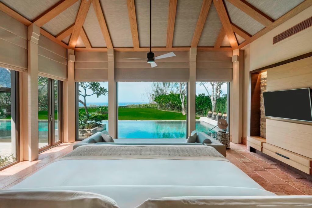 Schlafzimmer mit Panoramablick auf privaten Pool und Ozean durch große Fenster.