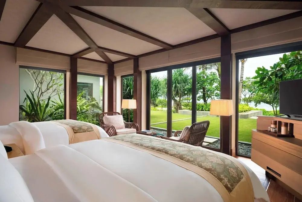 Helles Schlafzimmer mit Gartenblick und großer Fensterfront in einer Oceanfront Villa