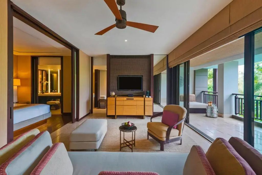 Helles Wohnzimmer der Suite mit Sofa und Zugang zum Balkon mit Gartenblick