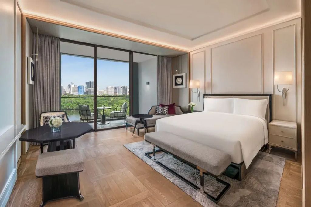 Luxuriöses Doppelzimmer mit Balkonblick auf den Lumpini Park und die Stadt Bangkok.