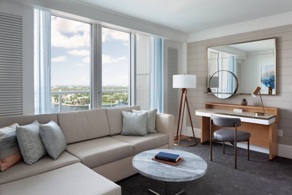 Elegantes Wohnzimmer mit Sofa, Marmortisch und großem Fenster mit Wasserblick.