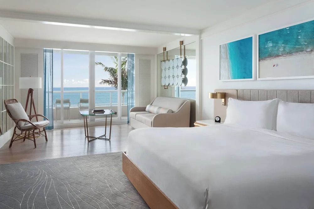 Gemütliches Zimmer mit Doppelbett und Glasfront. Zugang zu einem Balkon mit Meerblick.