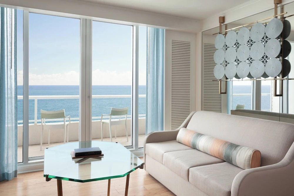 Wohnbereich mit Sofa und Glastisch. Zugang zum Balkon mit spektakulärem Meerblick.