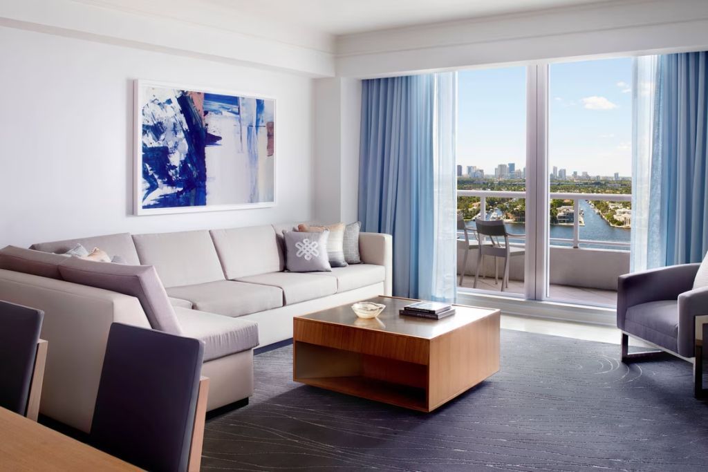 Wohnbereich der Suite mit modernem Sofa, Kunstwerk an der Wand und großem Fenster.