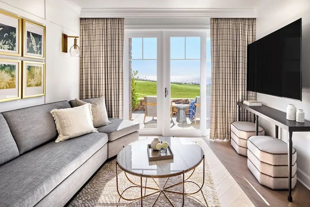Helle Suite mit stilvollem Sofa und Zugang zur Terrasse mit Meerblick