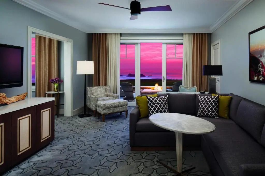 Luxuriöses Wohnzimmer der Suite mit Sofa und Blick auf den Sonnenuntergang am Meer