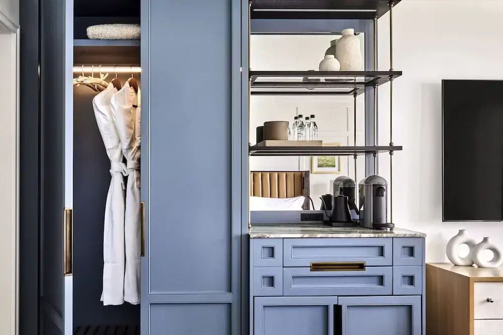 Garderobe mit Bademänteln und einer Kaffeemaschine auf einer Anrichte