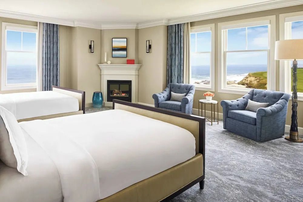 Luxuriöses Schlafzimmer mit zwei Betten, eleganten Sesseln und Meerblick.