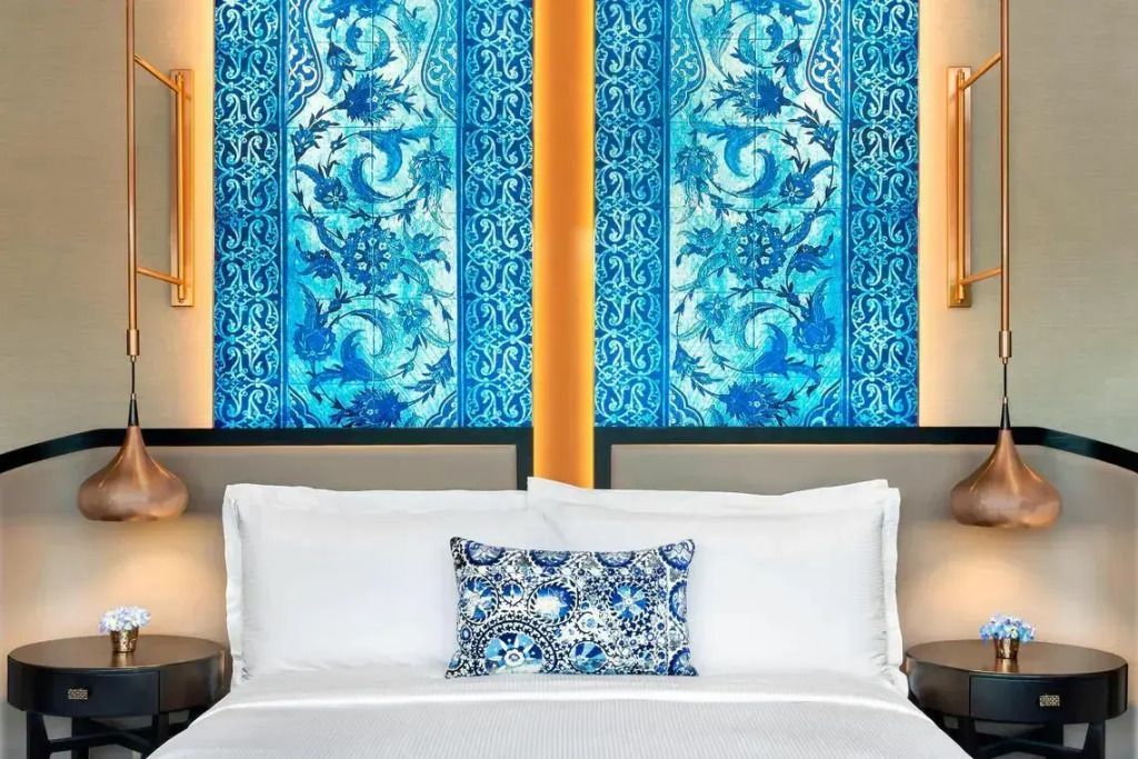 Bett mit blauen dekorativen Kissen und Mustern an der Wand