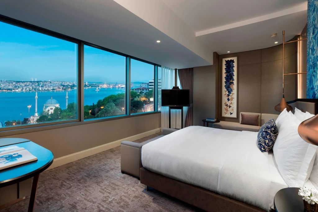 Geräumiges Schlafzimmer mit Panoramafenster und Blick auf den Bosporus bei Dämmerung.