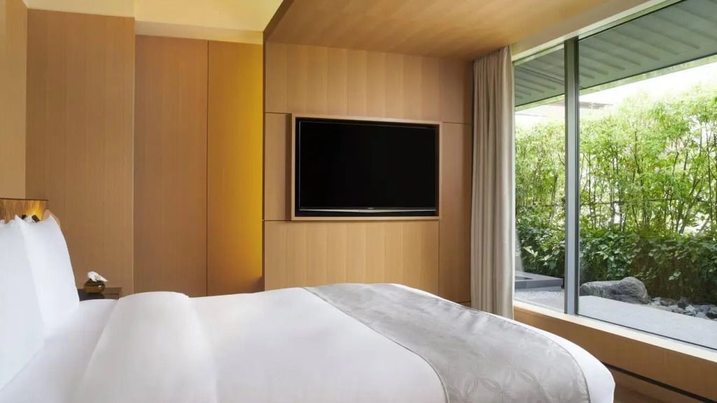 Elegantes Schlafzimmer mit Fernseher und Blick auf den Zen-Garten im Ritz-Carlton Kyoto.