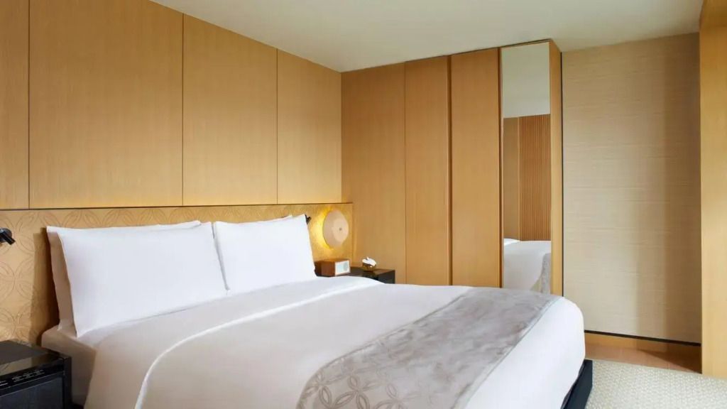 Doppelbett mit Holzverkleidung in heller, moderner Suite