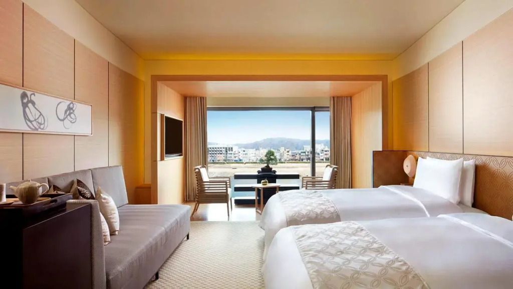 Hotelzimmer mit großem Fenster und Blick auf den Fluss und Stadtlandschaft.