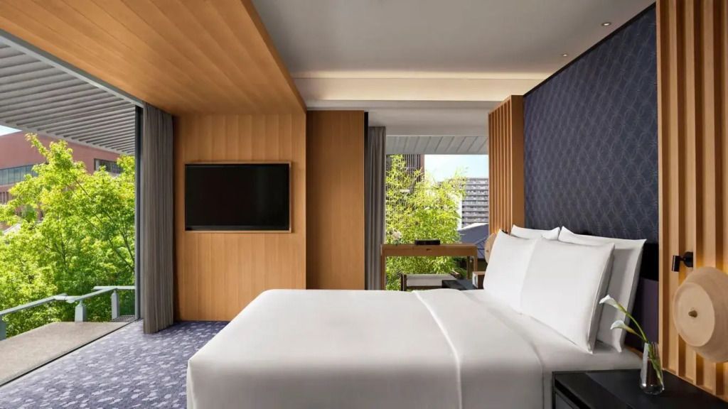 Komfortables Doppelbett mit großen Fenstern und grünem Ausblick in der Suite.