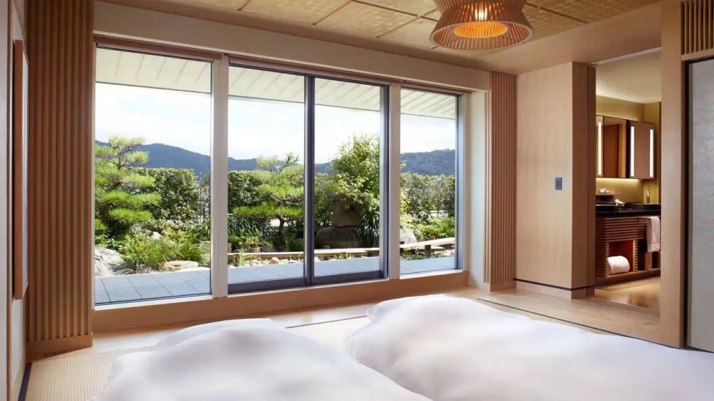 Große Fenster in der Suite mit Blick auf den grünen Garten und die Berge
